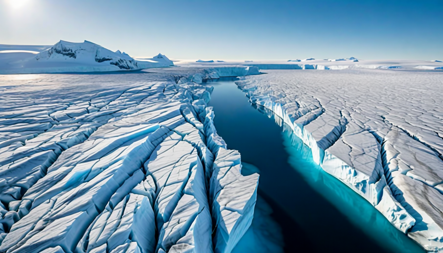 A crevassed ice surface split by a deep meltwater channel of intense blue water